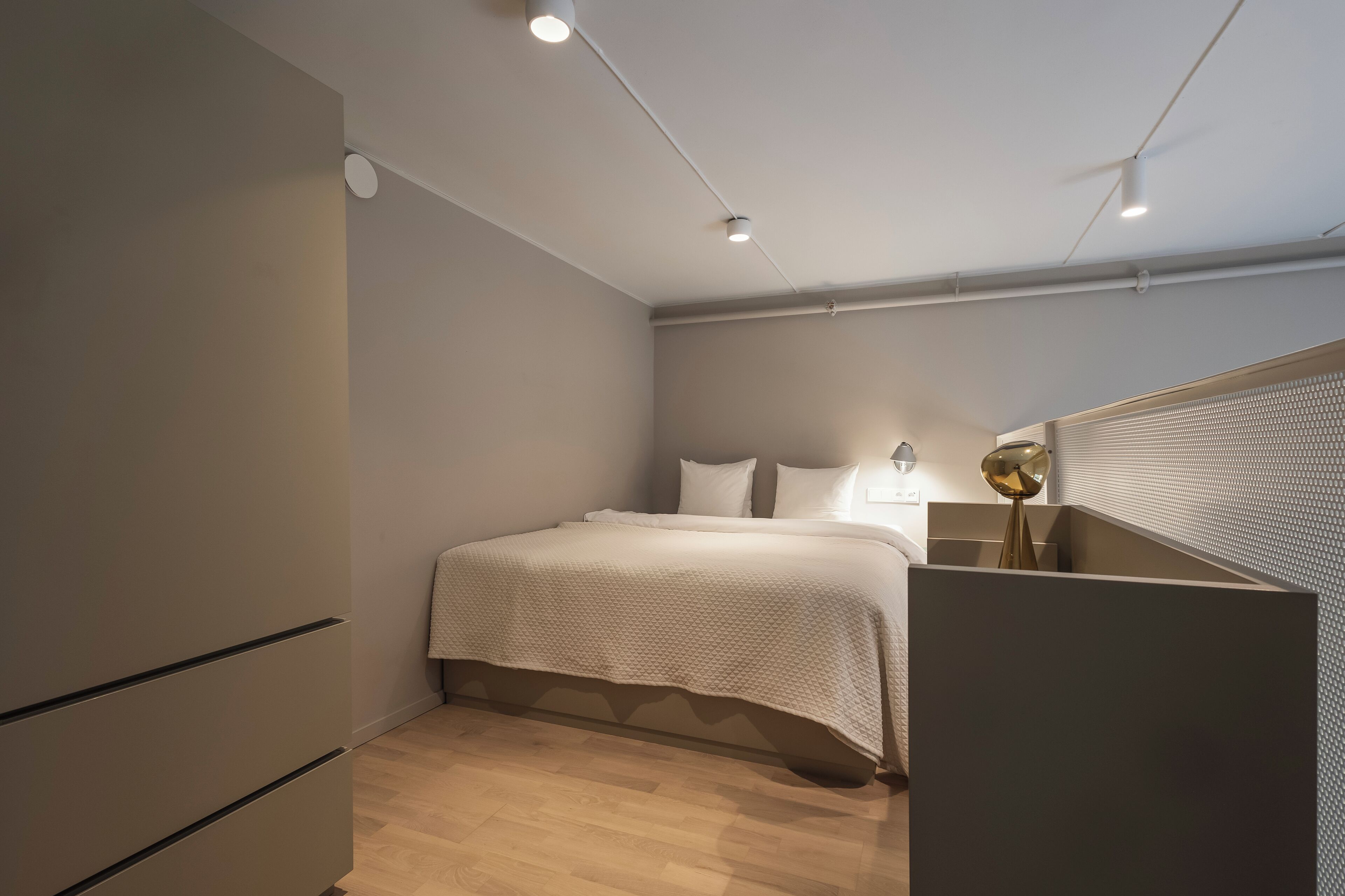 Un dormitorio moderno con cama, lámparas de noche y un armario.