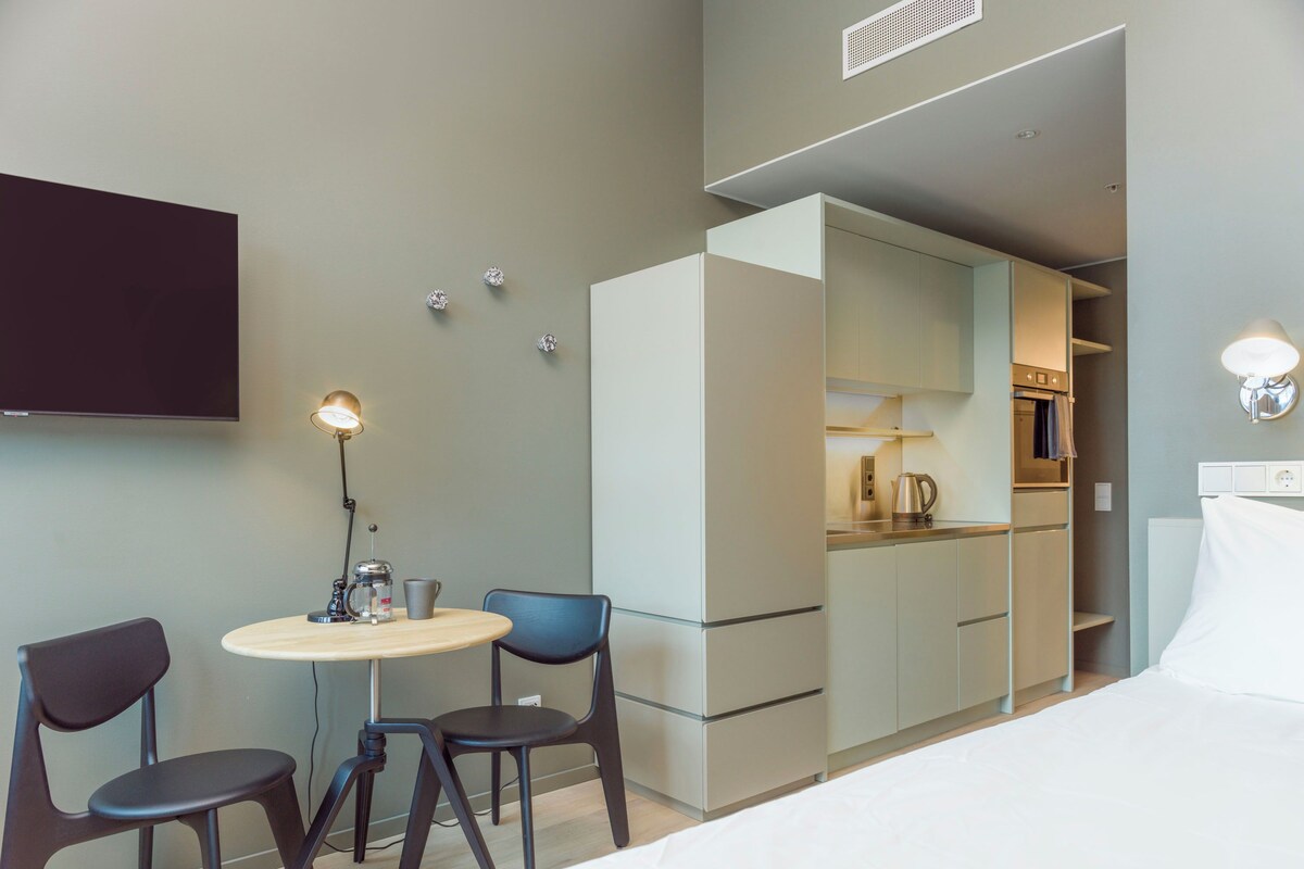 Une chambre d’hôtel équipée d’un lit, d’un bureau avec une chaise, d’une machine à café et d’une télévision.