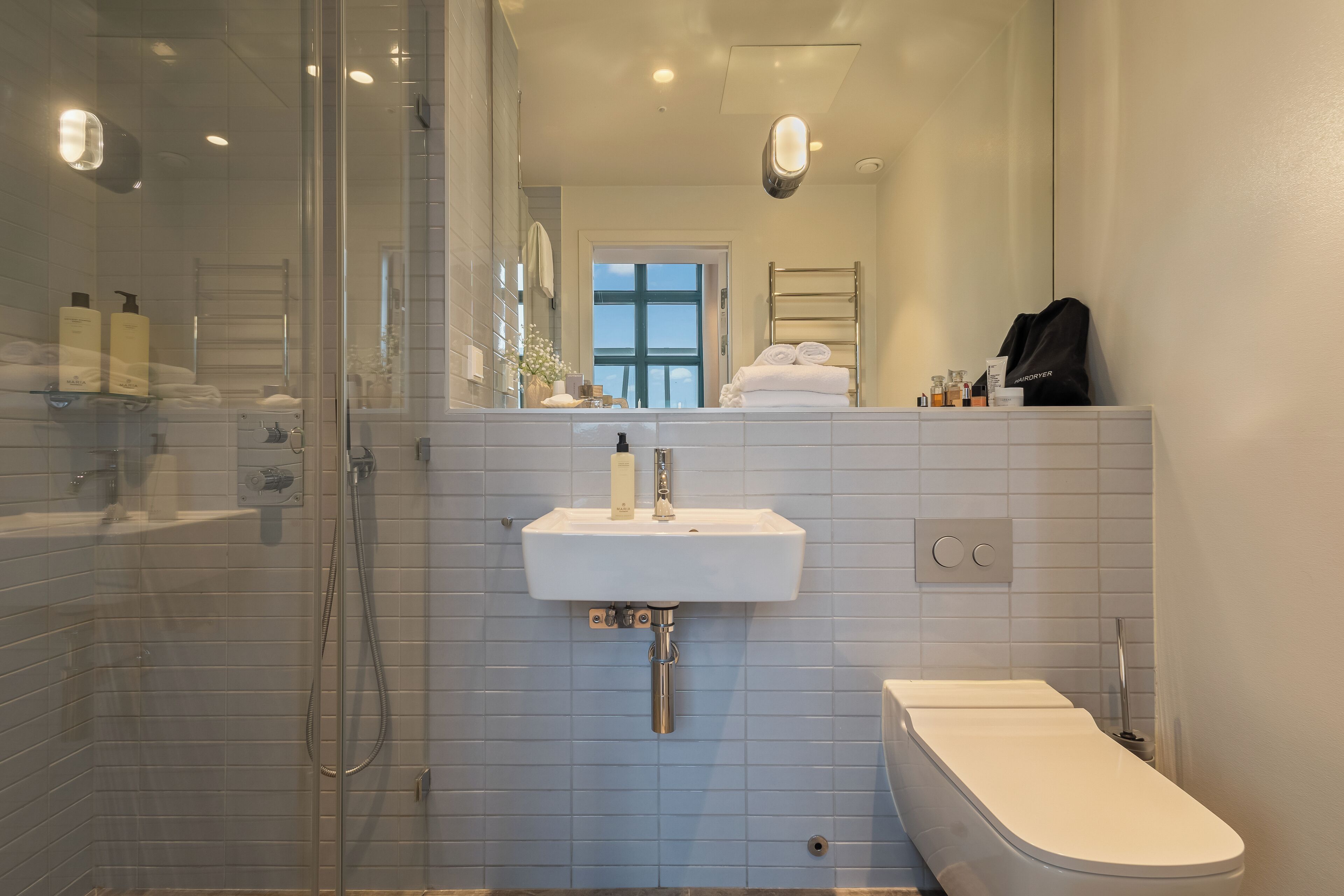 Ein modernes Badezimmer mit einer Duschkabine aus Glas, einem weißen Waschbecken und einer Toilette.