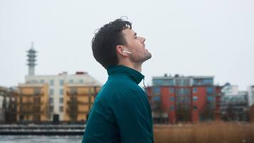 Une personne portant une veste turquoise, debout devant un paysage urbain.