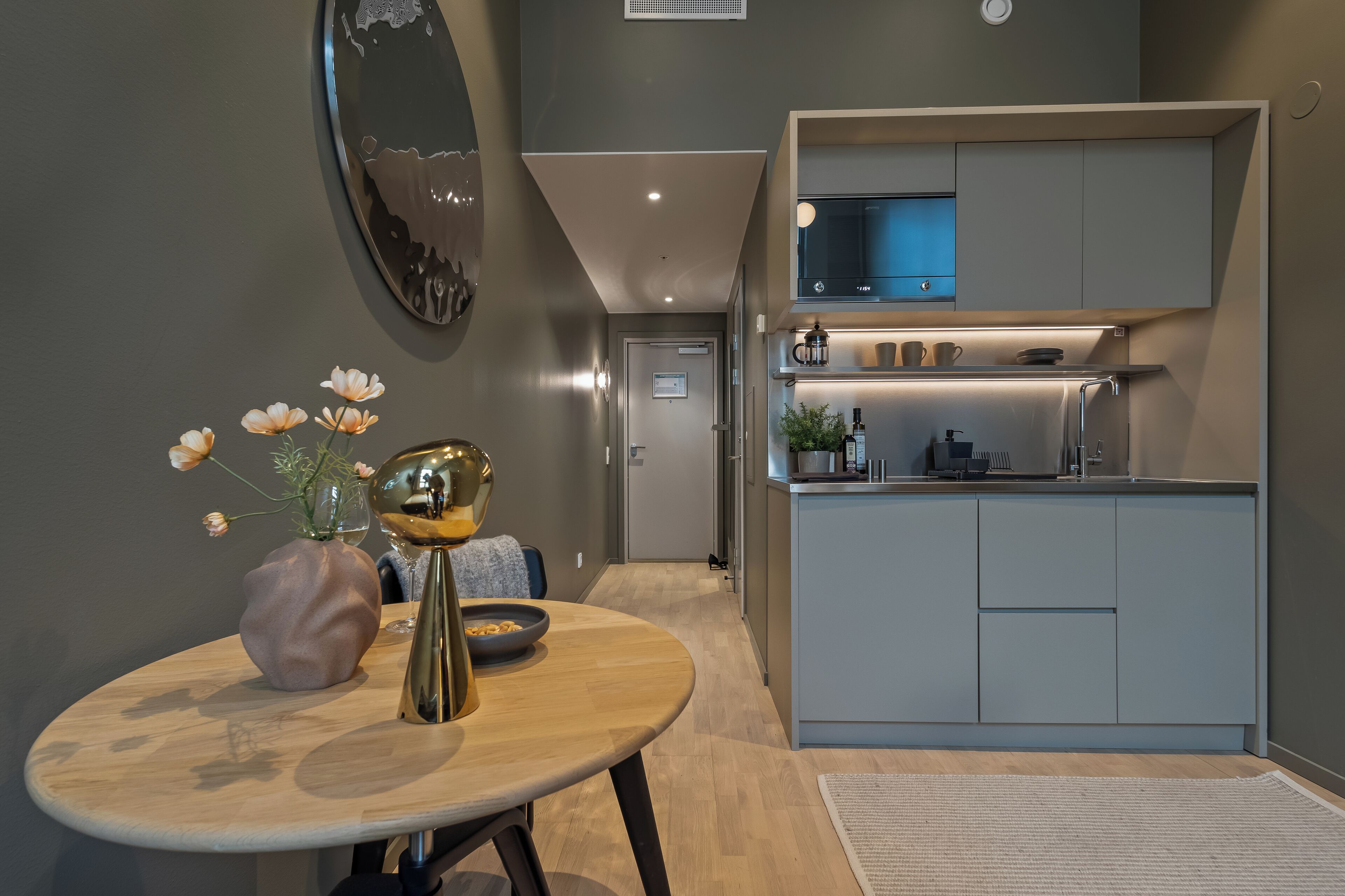A modern kitchen with grey cabinets, a built-in microwave, and a small countertop.