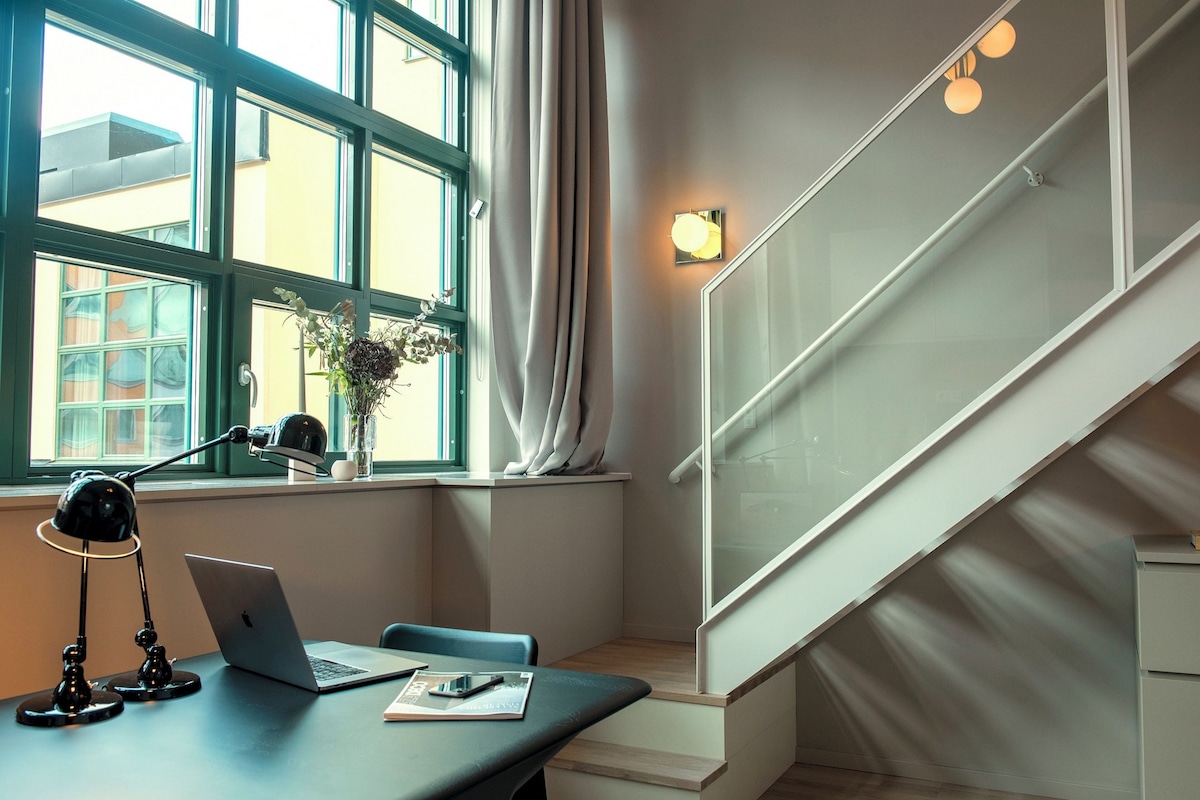 A modern office space with a desk, laptop, and lamp.