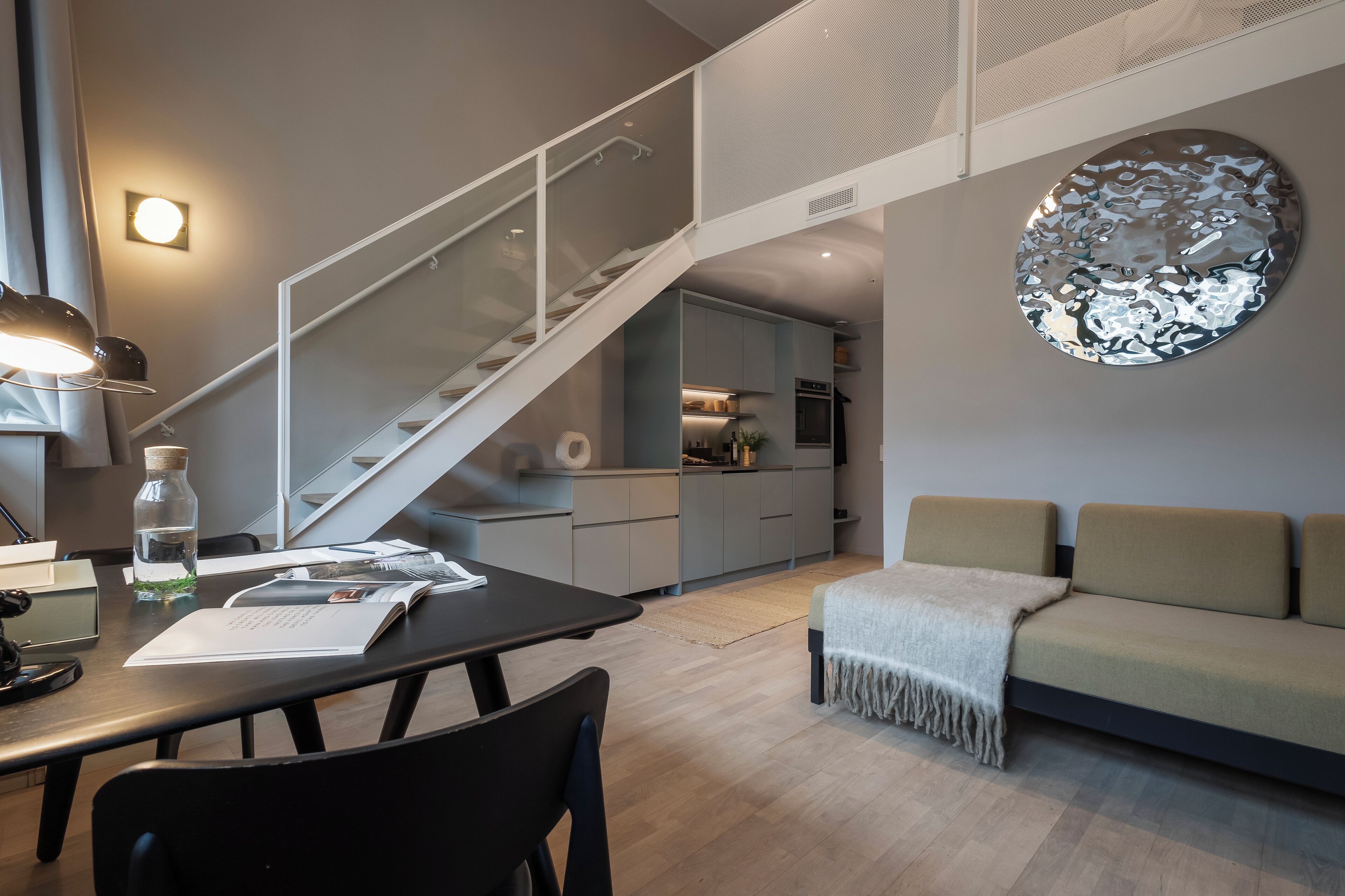 Un espai de vida modern amb una escala, una zona de menjador i un sofà.