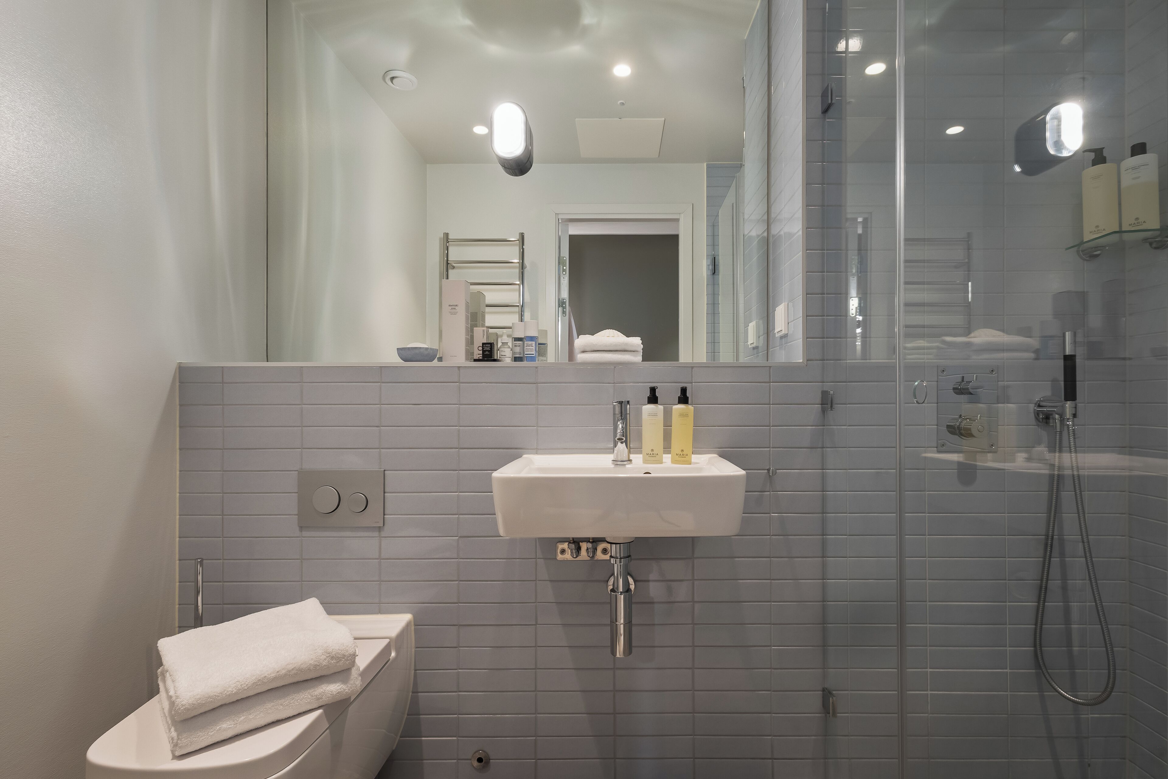A modern bathroom with a white sink, mirror, and glass shower enclosure.