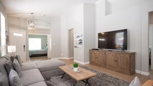 A modern living room with a sectional sofa, a flat-screen TV, and a wooden coffee table. - 35% off Special Green Valley Gem! 3/2 Single Story (Henderson)