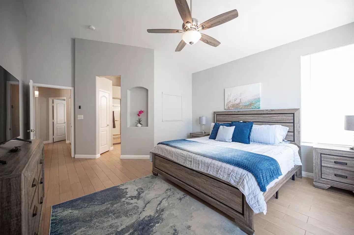 A bedroom with a wooden bed, a ceiling fan, a nightstand, and a window.