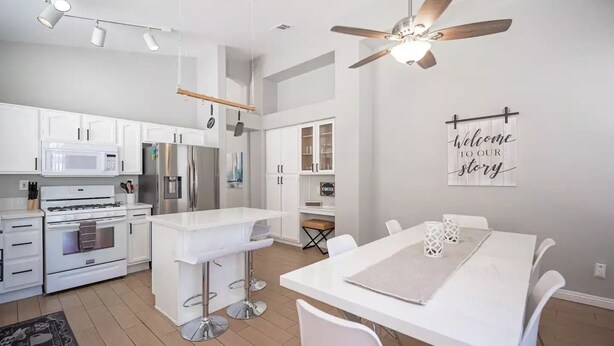 A modern kitchen with white cabinets, stainless steel appliances, and a bar area with stools. - 35% off Special Green Valley Gem! 3/2 Single Story (Henderson)
