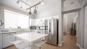 A modern kitchen with a central island, stainless steel appliances, and white cabinetry. - 35% off Special Green Valley Gem! 3/2 Single Story (Henderson)