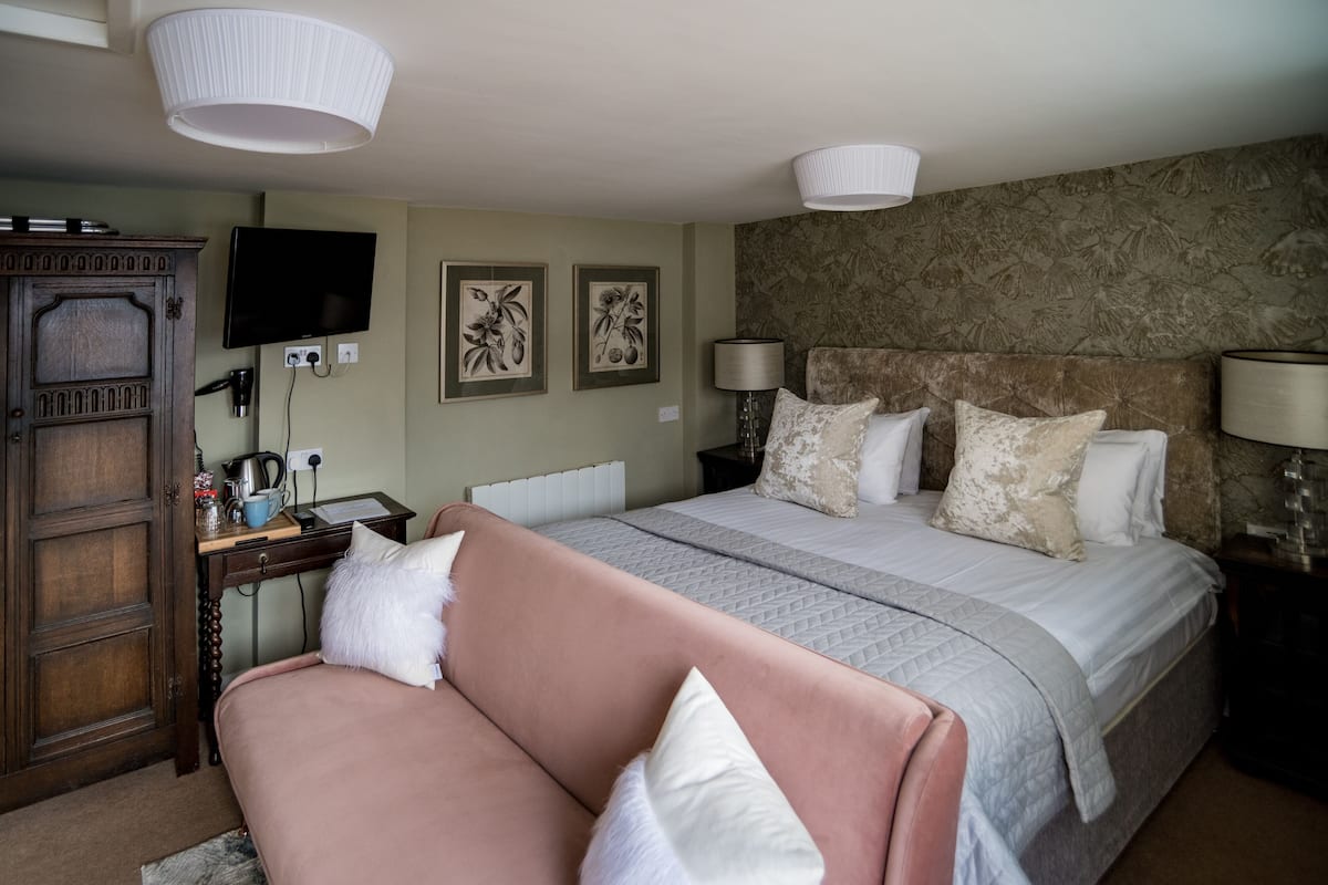 A bedroom with a bed, a desk, a TV, and a wardrobe.