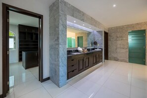 A modern bathroom with a marble vanity, a large mirror, and a green door.