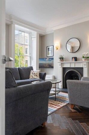 A living room with a fireplace, a sofa, a chair, and a small table.