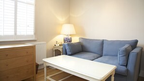 Una habitación con un sofá azul, una mesa blanca y un aparador de madera.