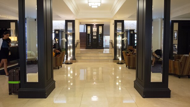 Un vestíbulo de hotel con piso pulido, una escalera y zonas de estar.