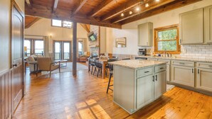 A spacious kitchen with wooden floors, a large island, and a dining area with a view. - Fab-VIEW-lous 4-bdrm cabin w/ Hottub, LUX theater, outdoor fireplace & firepit (Morganton)