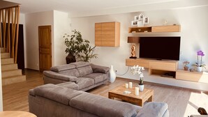A modern living room with a sectional sofa, a TV, and a wooden coffee table. - Maison Paisible (VEDENE)