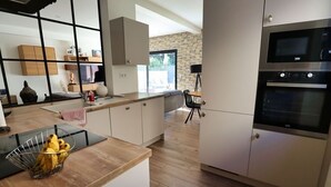 A modern kitchen with white cabinets, a black countertop, and a built-in oven. - Maison Paisible (VEDENE)