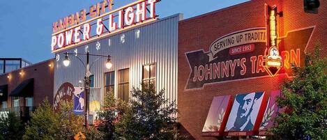 Un edificio con un letrero de neón que dice "Kansas City Power & Light" y otro letrero para "Johnny's Tavern" con un letrero de neón.