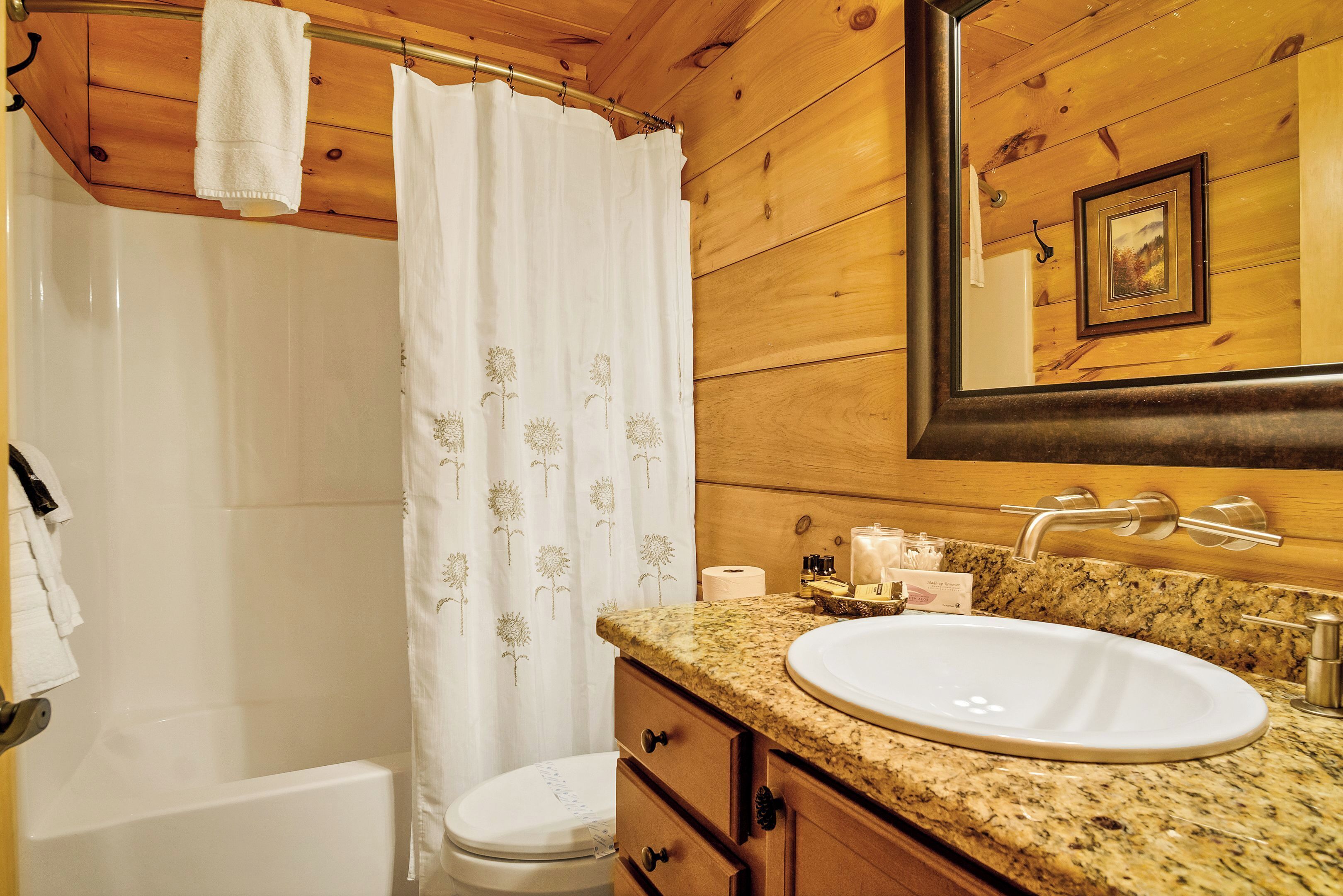 Ein Badezimmer mit einem weißen Waschbecken, einer Holzausstattung und einer Duschvorhang mit Blumenmuster.
