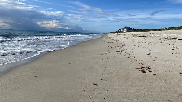 A beach with a house on the right, waves, and a partly cloudy sky. - Tranquil Vero Beach Home – Private Pool + Special Booking Discounts! (Vero Beach)