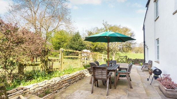 A patio area with a stone floor, wooden furniture, and a green umbrella. - The Farmhouse - UK33419 (West Witton, near Leyburn)