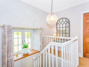 A staircase with white railings leading to a landing. A window with floral curtains and a vase of flowers is visible on the landing. - The Farmhouse - UK33419 (West Witton, near Leyburn)