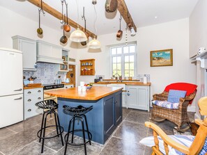 A kitchen with a large island, bar stools, and hanging pots. - The Farmhouse - UK33419 (West Witton, near Leyburn)