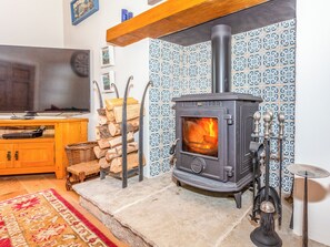 Una sala de estar acogedora con una chimenea de leña, un televisor y una pared de azulejos con diseño.