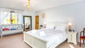 A bedroom with a bed, bedside tables, a chair, a window with curtains, a mirror, and a chandelier. - The Farmhouse - UK33419 (West Witton, near Leyburn)