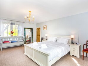 A bedroom with a bed, bedside tables, a chair, a window with curtains, a mirror, and a chandelier. - The Farmhouse - UK33419 (West Witton, near Leyburn)