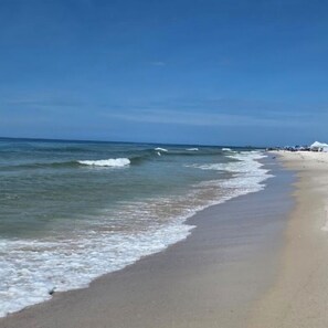Een strand met golven, een heldere lucht en een zandstrand.