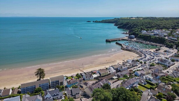A coastal town with a beach, a marina, and residential buildings.