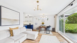 A modern living room with a sofa, a dining table, and a kitchen in the background.