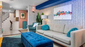 A modern living room with a sofa, ottoman, and a painting on the wall. - Artistic Craftsman Style Home Downstairs Apartment (Portland)