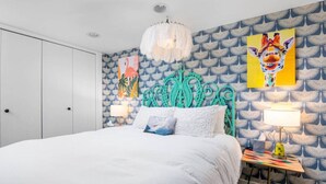 A bedroom with a bed, a nightstand, a wall with patterned wallpaper, and a ceiling light. - Artistic Craftsman Style Home Downstairs Apartment (Portland)