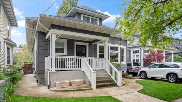 A two-story house with a front porch, a driveway, and a well-maintained lawn. - Artistic Craftsman Style Home Downstairs Apartment (Portland)