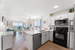 A modern kitchen with white cabinetry, a built-in oven, and a microwave.