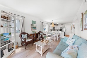 A spacious living area with a sofa, chairs, a dining table, and a kitchen in the background. - Ocean Garden Villas E1-2BR/2BA Oceanfront Condo in Crescent Beach (North Myrtle Beach)