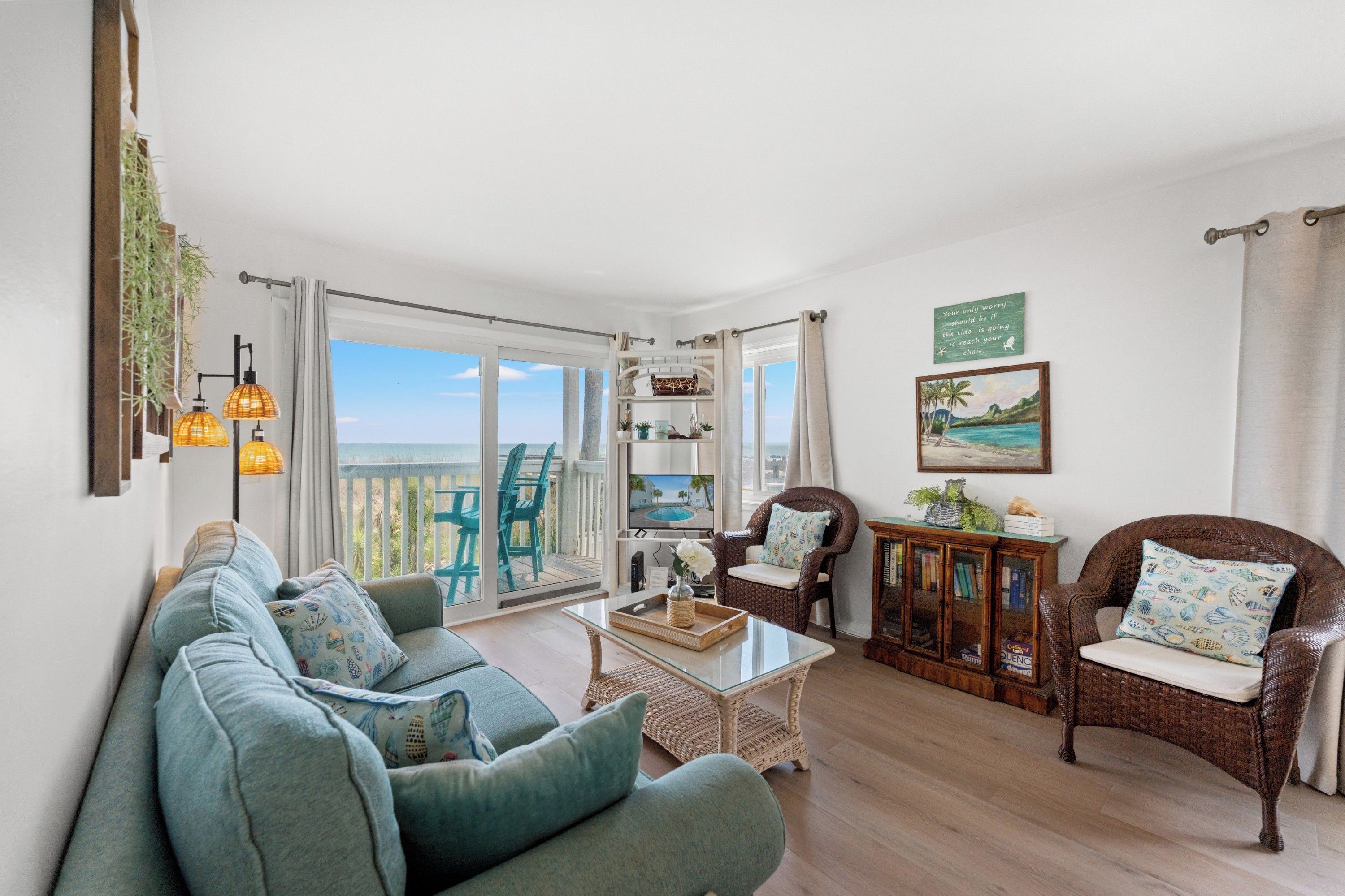 A living room with a sofa, chairs, a coffee table, and a view of the sea through large windows.