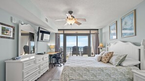 A bedroom with a bed, a desk, a dresser, a ceiling fan, and a view of the outdoors. - Beachwalk Villas 104-3BR/3BA Condo in Cherry Grove (North Myrtle Beach)