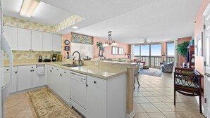 A spacious kitchen with white cabinets, a large island, and a dining area with a view.