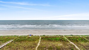 A beach with a path leading to the water, a sandy beach, and the ocean.