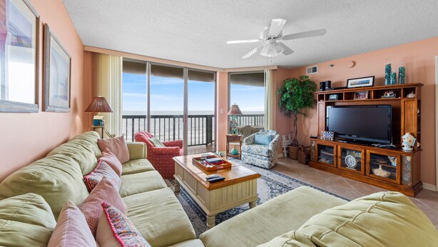 A spacious living room with a large sofa, a coffee table, and a television on a wooden stand.