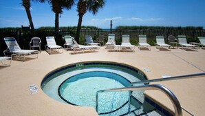 A swimming pool with lounge chairs and palm trees in the background.