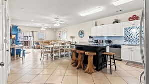 Una cocina amplia con una isla central, armarios blancos y un salpicadero de azulejos.