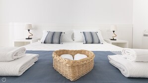A neatly made bed with white linens, two striped pillows, and a wicker basket filled with folded towels. - Rivazzurra Homes - 3 (Termoli)