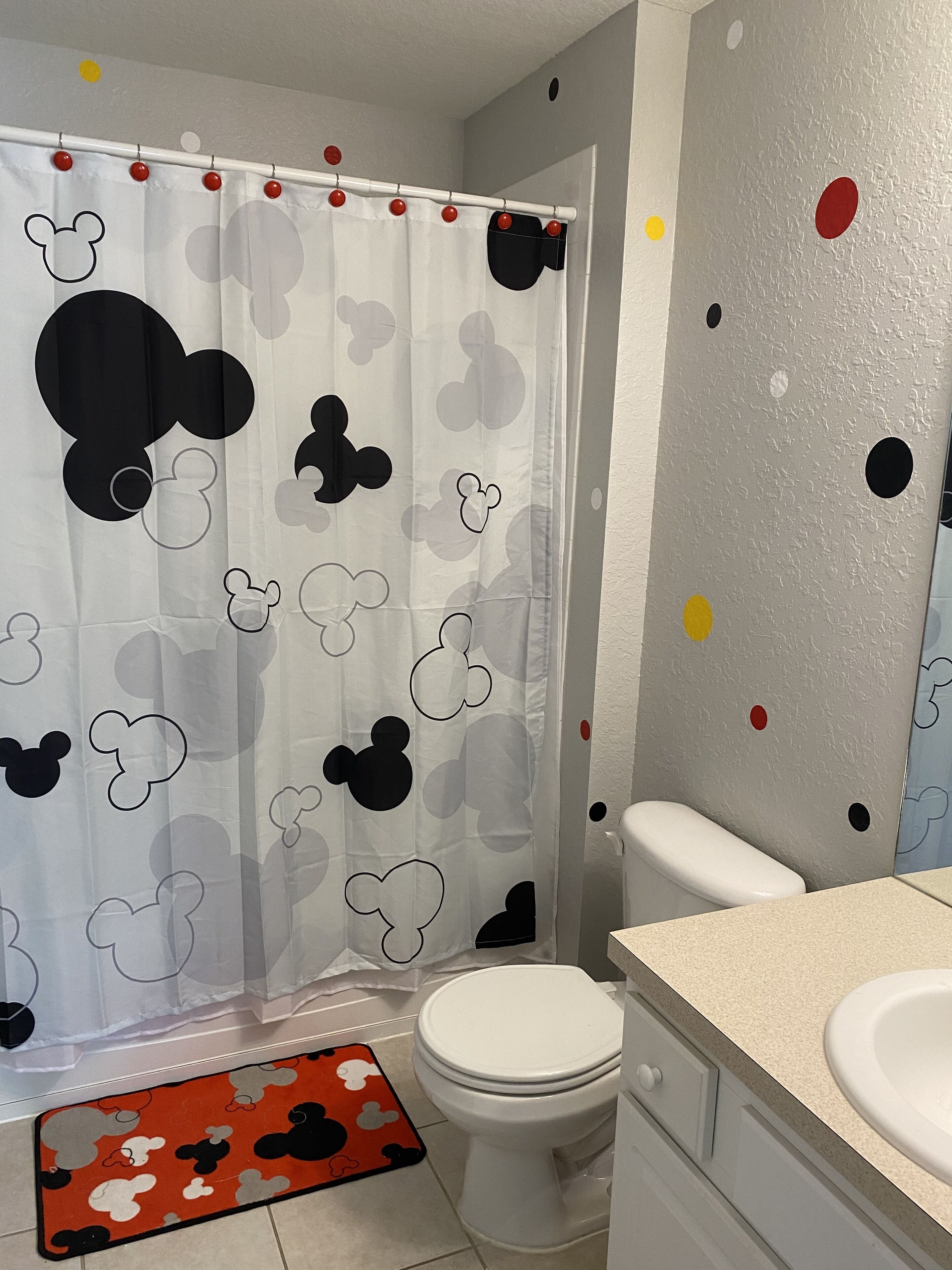 A bathroom with a Mickey Mouse themed shower curtain, a toilet, and a sink.