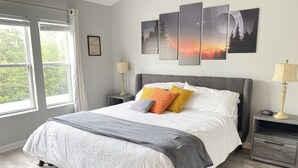 A neatly arranged bedroom with a large bed, two bedside tables, and a window with curtains.
