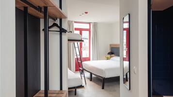 Une chambre d’hôtel de taille réduite, équipée d’un lit superposé, d’un bureau et d’un miroir.