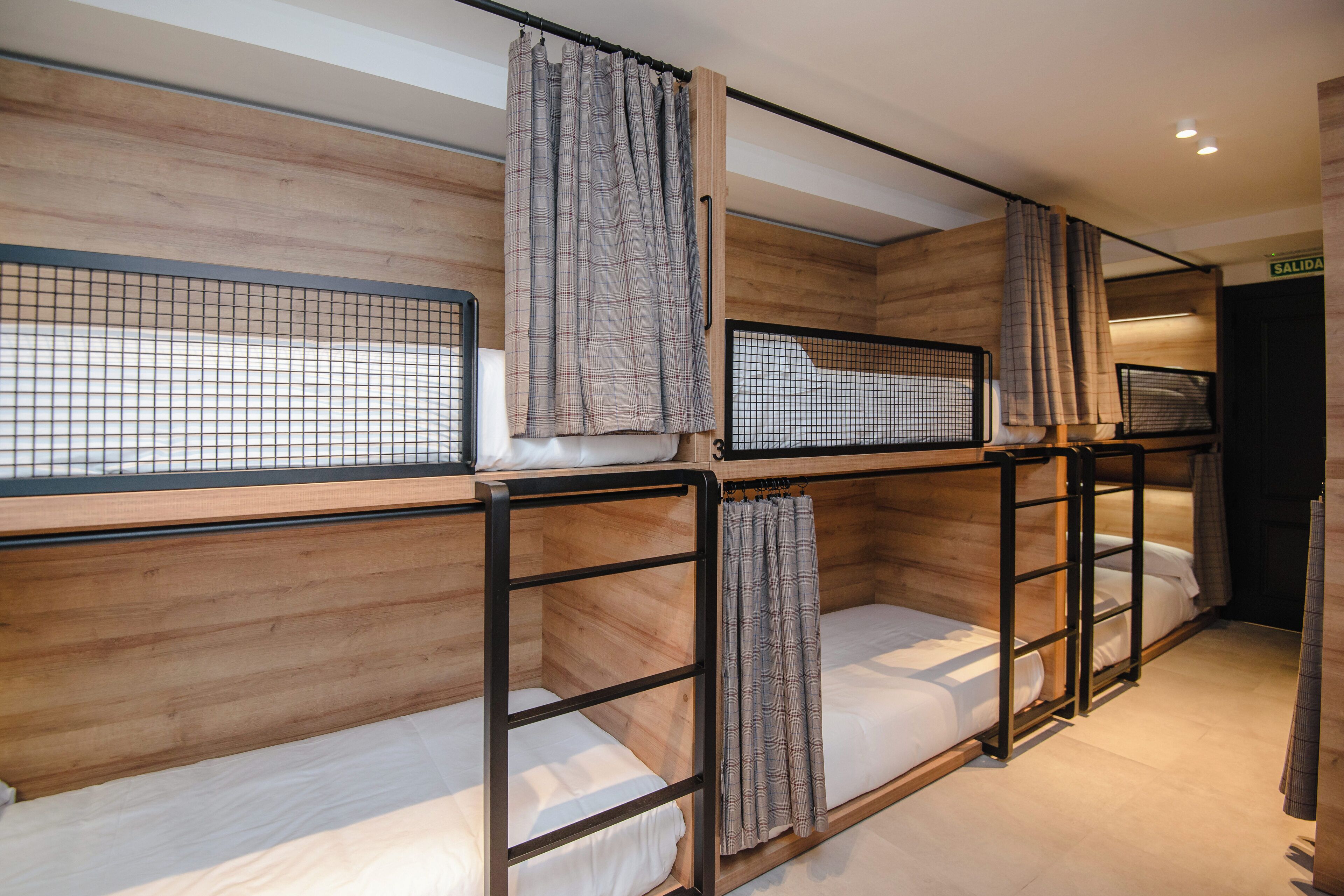 Una habitación con literas, paredes de madera y cortinas.