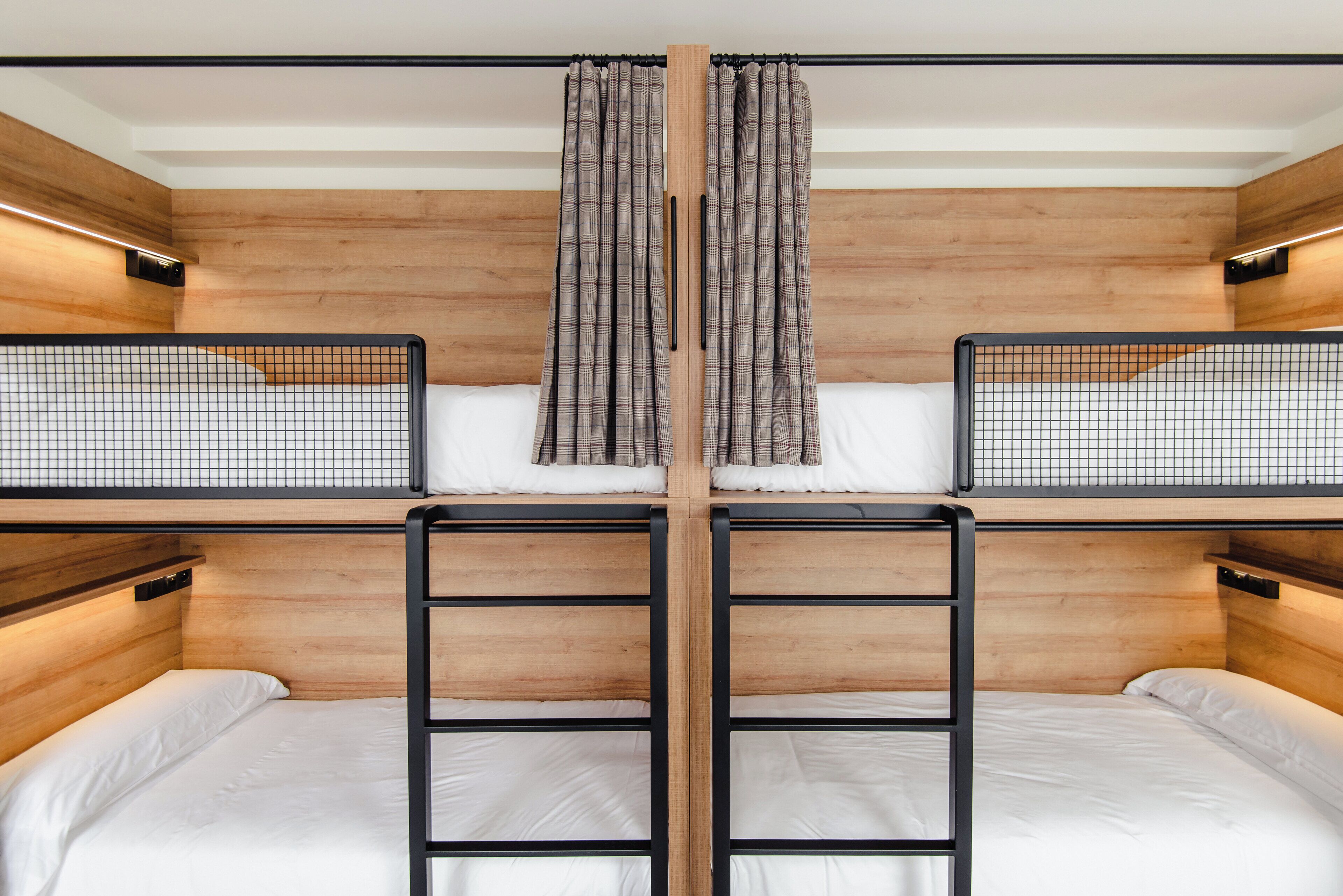 A bunk bed room with wooden walls, a central curtain, and a metal ladder.